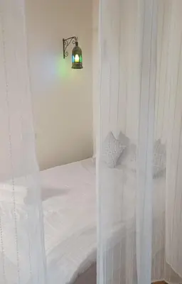 a bedroom with a white bed with a light on it at Dar Ayoub in Fès
