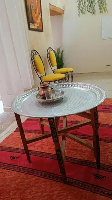 a glass table with two yellow chairs on a rug at Dar Ayoub in Fès