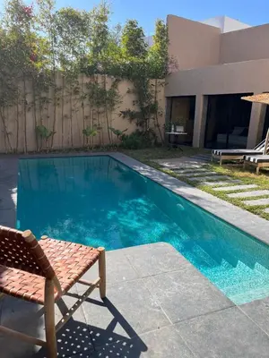 a swimming pool with a chair next to a house at Escape Villa City center pool 3 bedrooms in Oulad Akkou