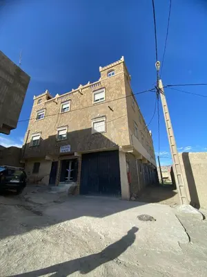 an old brick building with a ladder in front of it at Maison d'hôtes Moussem des fiançailles in Imilchil