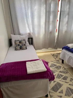 a bedroom with a bed with purple sheets and a window at Hostel dallas Warzazate in Ouarzazate