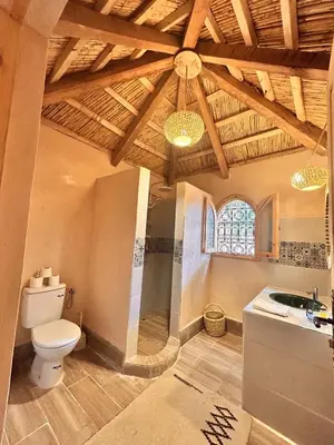 a bathroom with a toilet and a sink and a window at Serenity Lodge Zagora Guest House Restaurant & Desert Excursions in Zagora