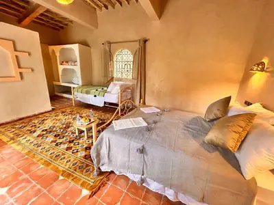 a bedroom with a large bed and a table at Serenity Lodge Zagora Guest House Restaurant & Desert Excursions in Zagora