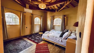 a bedroom with a large bed and two windows at Serenity Lodge Zagora Guest House Restaurant & Desert Excursions in Zagora