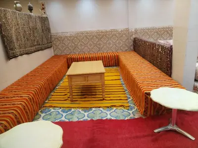 an orange couch with a table and a stool at almou auberge Imilichil in Imilchil