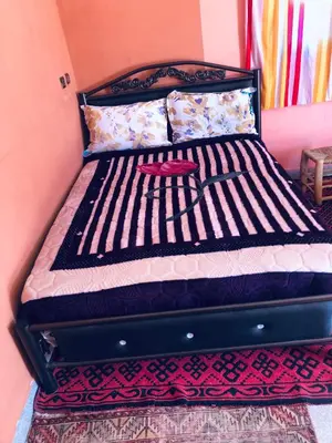 a bed with a black frame in a room at Hotel Kasbah Telouet in Telouet