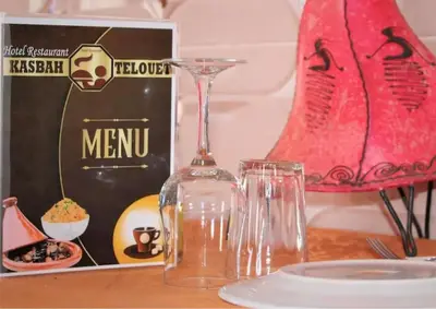 a table with a wine glass and a bottle on it at Hotel Kasbah Telouet in Telouet
