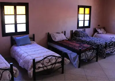 a room with three beds and a table and windows at Hotel Kasbah Telouet in Telouet