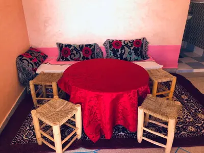 a room with a bed with a table and two stools at Hotel Kasbah Telouet in Telouet