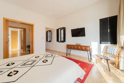 a bedroom with a bed and a table and a television at Luxury 5-Suite Villa with Heated Pool, Steam Room & Games in Marrakech