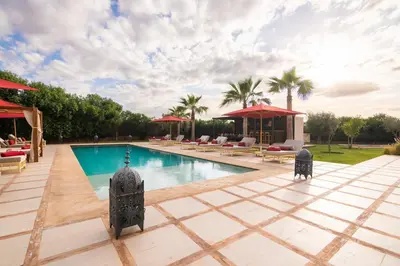 a swimming pool with chairs and umbrellas in a resort at Luxury 5-Suite Villa with Heated Pool, Steam Room & Games in Marrakech