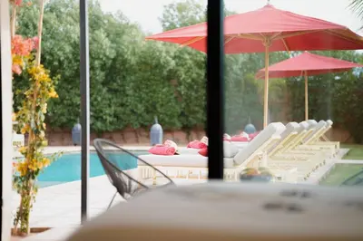 a group of chairs and umbrellas next to a pool at Luxury 5-Suite Villa with Heated Pool, Steam Room & Games in Marrakech