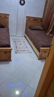 a room with two beds and a rug on the floor at A new, lively apartment in Oulad Akkou