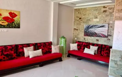 a living room with red couches and a painting at A new, lively apartment in Oulad Akkou