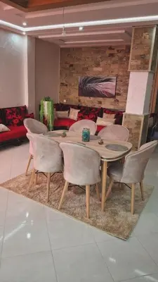 a dining room with a table and chairs on a rug at A new, lively apartment in Oulad Akkou
