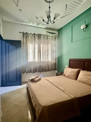 a bedroom with a large bed with a blue wall at charmant appartement in Fès