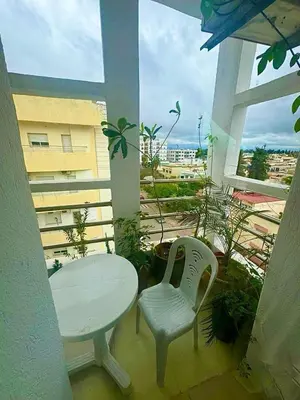 a white table and chair on a balcony with a window at apartment champs de cours in Fès