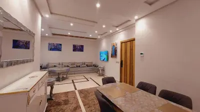 a living room with a table and a couch at Tanger Apt Near Train & Mall in Oulad Akkou