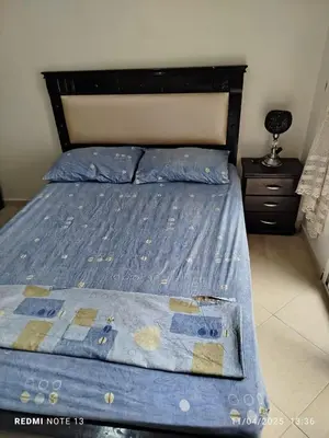 a bed with a blue comforter on top of it at appartement martil in Oulad Akkou