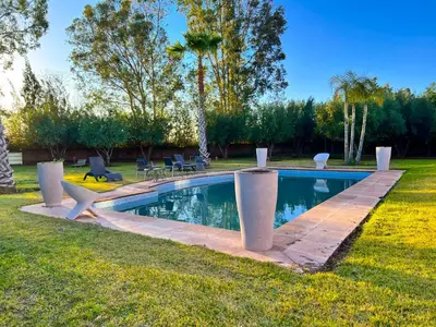 a swimming pool in a grassy yard with trees at Villa Zeen Garden in Marrakech