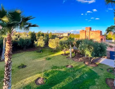 an aerial view of a park with palm trees and a castle at Villa Zeen Garden in Marrakech
