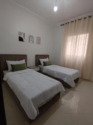 two beds in a white room with a window at Diar kamiliya in Meknès