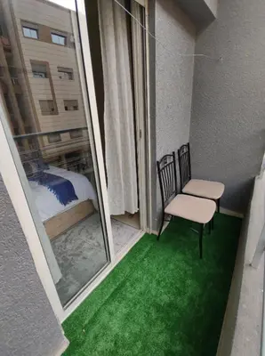 a balcony with a chair and a window with green grass at Diar kamiliya in Meknès