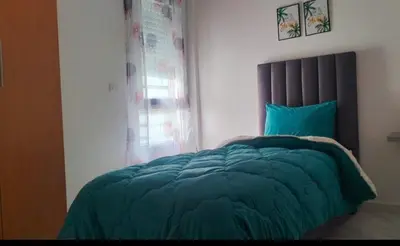 a bedroom with a bed with a blue comforter and a window at Appartement la perle in Fès