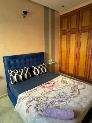 a bed with a blue headboard in a room at Appartement F in Fès