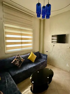 a living room with a blue couch and a chair at Appartement F in Fès