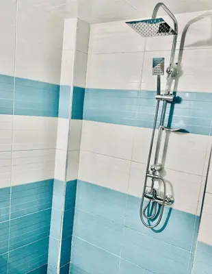 a shower with blue and white stripes in a bathroom at Appartement F in Fès
