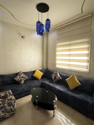 a living room with a blue couch with pillows at Appartement F in Fès