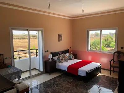 a bedroom with a bed and two windows at Beautiful villa with large private pool in Zaouia Sidi Rahkal