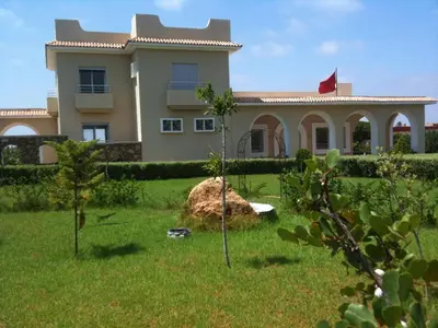 a house in the middle of a yard with a rock at Beautiful villa with large private pool in Zaouia Sidi Rahkal