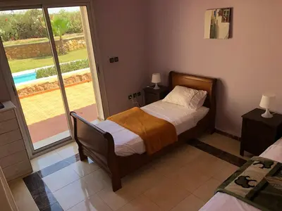 a bedroom with a bed and a sliding glass door at Beautiful villa with large private pool in Zaouia Sidi Rahkal