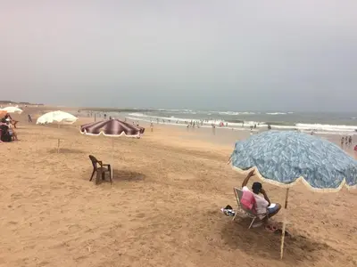 a person sitting in a chair under an umbrella on a beach at Beautiful villa with large private pool in Zaouia Sidi Rahkal