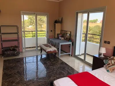 a living room with a bed and a table and windows at Beautiful villa with large private pool in Zaouia Sidi Rahkal