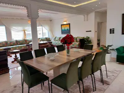 a dining room table with green chairs and a table and flowers at villa saada in Fès