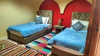 a bedroom with two beds and a rug at Kasbat Taslit chez l'habitant in Tabount