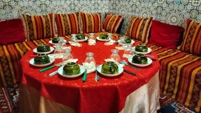 a table with a red table cloth with teapots on it at Kasbat Taslit chez l'habitant in Tabount