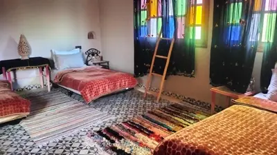 a room with two beds with colorful curtains and a rug at Kasbat Taslit chez l'habitant in Tabount