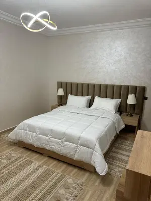 a bedroom with a large white bed with two lamps at Al khaima in Oulad Akkou