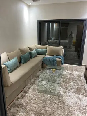 a living room with a couch with blue pillows at Duplex in Oulad Akkou