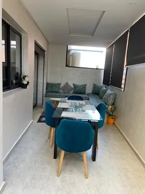 a living room with a table and blue chairs at Duplex in Oulad Akkou