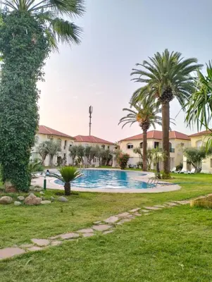 a pool in a yard with palm trees at Azure's House in Fès