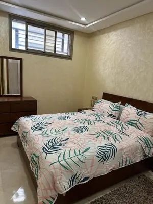 a bedroom with a bed with a comforter and a window at apartamente á fes in Fès