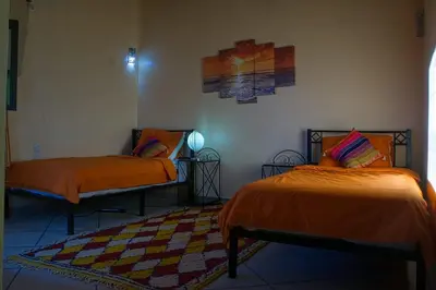 a room with two beds with orange sheets and a rug at Lamtounipalace in Ouarzazate