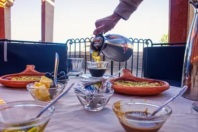 a person pouring food into bowls on a table at Lamtounipalace in Ouarzazate