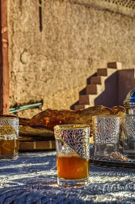 a table with glasses of beer and a loaf of bread at Lamtounipalace in Ouarzazate