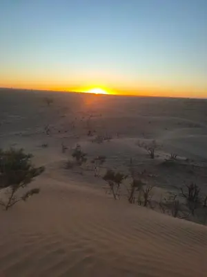a sunset in the desert with the sun setting at Sahara Luxury Room and Tours in Kasr Bounou